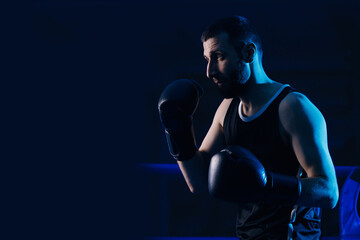 Fototapeta na wymiar Man boxer trains punches kick on ring, dark background. Concept training sport boxing