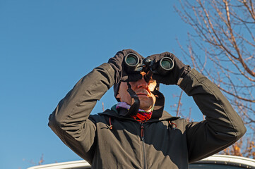 A man with binoculars bird watching on the lake.
