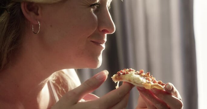 Woman, pizza and eating slice for meal or nutrition snack on weekend for carbs, dinner or vacation. Female person, dough and cheese in home for unhealthy joy lunch for fast food, hunger or takeout