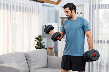 Athletic body and active sporty man lifting dumbbell weight for effective targeting muscle gain at gaiety home as concept of healthy fit body home workout lifestyle.