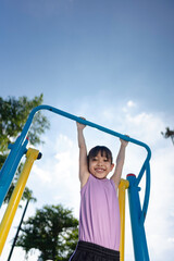 Obraz premium A girl is playing climbing and exercising at the playground.