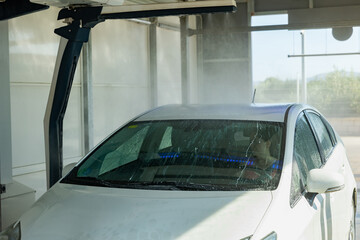 Process of car washing with driver inside. Automatic car wash machine in work.
