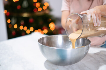 Niña pequeña añadiendo alimento batido en un bol cromado.