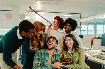 Business man celebrating birthday and having a party with diverse colleagues