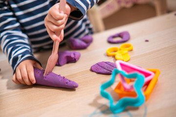 Manos de niña de  2 años jugando con plastilina casera y moldes. Jugar con la plastifica en casa,...