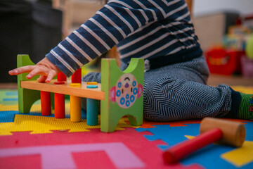 Bebé entretenido con juego sensorial en el suelo. Juguete Montessori educativo de madera.