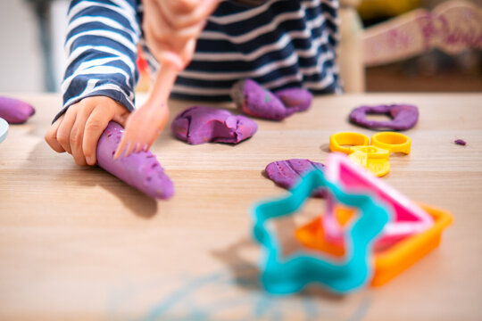 Manos de ni&ntilde;a de  2 a&ntilde;os jugando con plastilina casera y moldes. Jugar con la plastifica en casa, juguetes educativos para ni&ntilde;os Montessori. Juegos creativos para ni&ntilde;os peque&ntilde;os. 