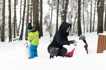 Mother With Kids Playing Outdoor in Winter Forest