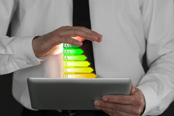 Energy efficiency rating coming out of tablet. Man using device, closeup