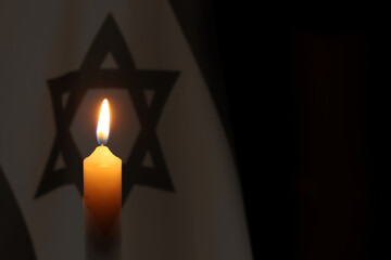 Burning candle against flag of Israel on black background - obrazy, fototapety, plakaty
