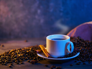 A white cup of black coffee on a wooden table with roasted coffee beans and copy space