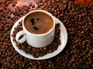 A white cup of fragrant freshly brewed black espresso coffee on the table with roasted coffee beans