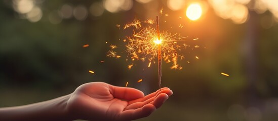 Burning sparkler in hand on blurred background of city street