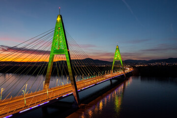 Fototapeta na wymiar Aerial view about the illuminated Megyeri bridge in a rare christmas decorations with stunning sunset at the background.