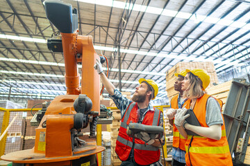 team Engineers standing by robotic arm and operating machine in factory. worker man control on tablet. Workers work at heavy machine robot arm. High-tech robot with a remote system in Wood factory.