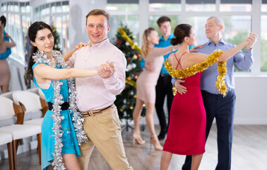Couples dancing during Christmas - men and women dancing tango or samba next to the Christmas tree