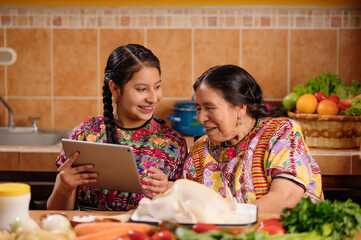 The granddaughter shows her grandmother the online recipe that they must follow in order to prepare...