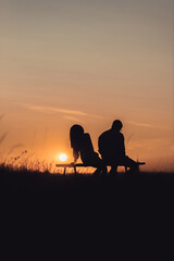 silhouette of  couple sitting on a bench at sunset