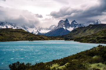 Fototapeta na wymiar Cuernos del Paine and Lago Pehoé under cloudy sky and hills at front
