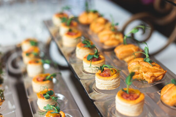 Beautifully decorated banquet catering table, with variety of with different food snacks appetizers on corporate birthday party event or wedding celebration, canape, salad, delicatessen setting