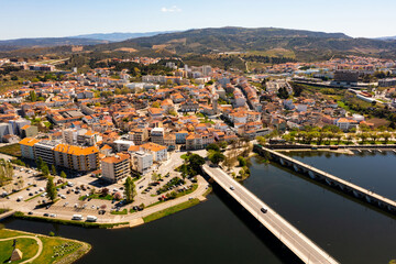 Fototapeta na wymiar Picturesque aerial view of residential districts of Mirandela city with brownish tiled roofs and two bridges crossing Tua river on spring day, Braganca, Portugal