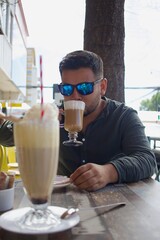 latino man sitting drinking coffee at a coffee shop