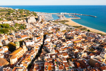 Scenic drone view of coastal small Catalan town of Arenys de Mar overlooking reddish roofs of...