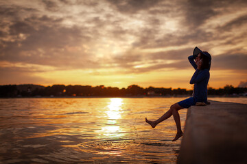 Adult Elegantly Dressed Woman Talking at Her Smartphone While Barefoot Enjoying the Moment on a Pier at Sunset Beautiful Warm Colors