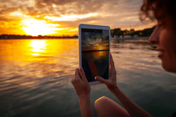 Adult Caucasian Woman Vacationer Photographing with Her Tablet of Colorful Sunset over Sea