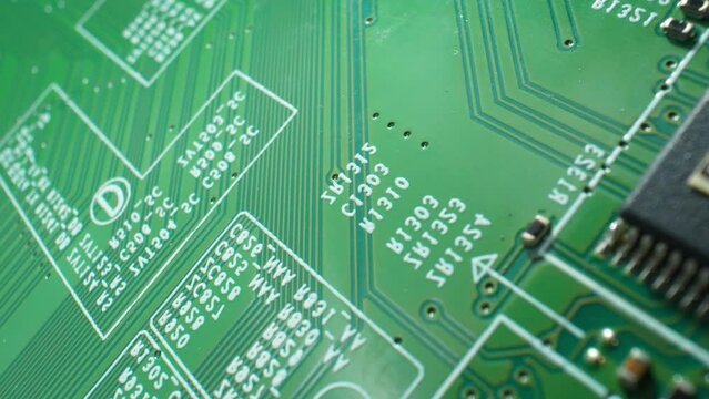 Dive into the captivating microcosm of a Printed Circuit Board (PCB) as the camera zooms in, revealing its delicate pathways and electronic wonders. Macro video footage. Technology concept.
