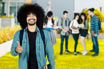 Male afro student smiling with friends standing at the back