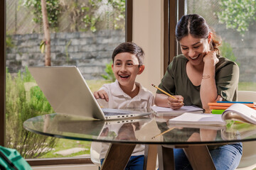 Mother and son have fun at home using a computer to study.