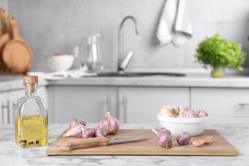 Obraz na płótnie Canvas Fresh raw garlic, knife and oil on white marble table