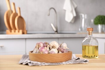 Bowl of fresh raw garlic and oil on wooden table in kitchen