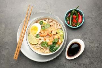 Delicious ramen with shrimps and egg in bowl served on grey table, flat lay. Noodle soup