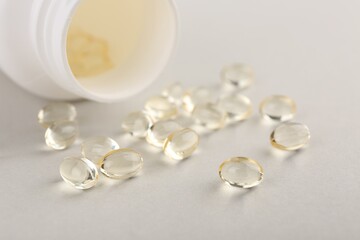 Vitamin capsules and bottle on light grey background, closeup