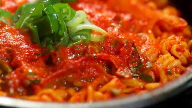 빨갛고 매운 한국식 해장 라면이 뚝배기에서 끓고 있는 