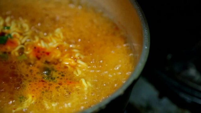 양은 냄비에서 끓는 물에 라면과 스프를 던져 넣고 끓인뒤 그릇에 담아낸 라면 상차림 