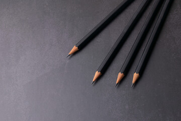 Lápices de grafito con punta afilada sobre fondo negro