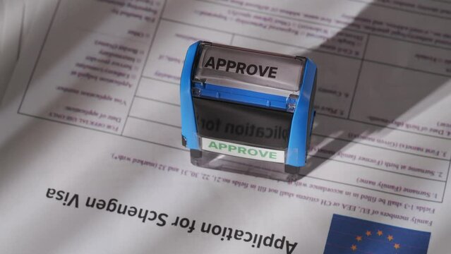 Close up shot of person visa application. Top view of european union visa document, female worker puts stamp with approve mark written on it.
