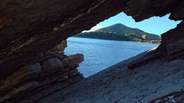 Enchanting view of stunning sea and majestic mountain. Picturesque sea bay harmonizing with grandeur of distant island mountain. View from cage hole