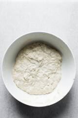 Focaccia dough rising in a white bowl, process of making focaccia, bread dough rising in a white mixing bowl	