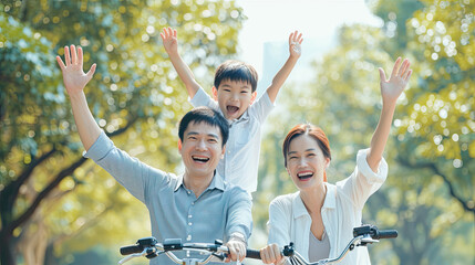 Happy Asian father and mother teach their son to ride a bicycle, Cheerful parent raise hands up in the air to support kid encouragement, family do activity together at park concept