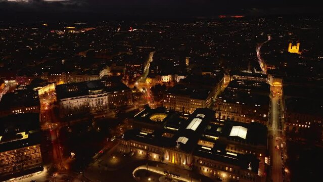 Aerial view of Parliament buildings and surrounding palaces in city center at night. Illuminated streets and large houses in metropolis. Vienna, Austria