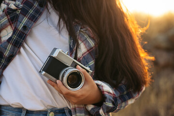 Unrecognizable woman taking photos with analog camera in the countryside - obrazy, fototapety, plakaty