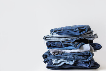 Stack of various shades of blue jeans on white background