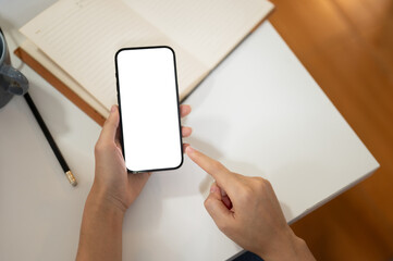 A female graphic designer using her smartphone at her office desk. A white-screen smartphone mockup.