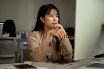 A dissatisfied businesswoman is reading emails, looking at her computer screen with a serious face.