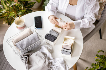 Unrecognizable woman sorting neatly folded linen cotton textile at container and basket on table