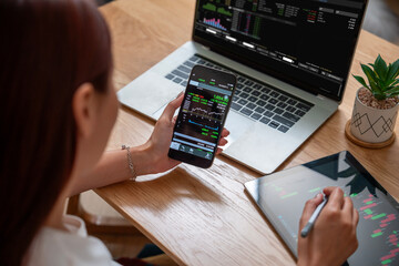 Close-up Shot of an Anonymous Woman Holding a Smartphone with a Stock Market Graph on Screen